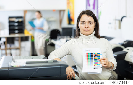 Woman employee of printing shop holds color chart in her hands 140273414
