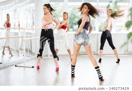 During lesson, girl learn to move and perform dance in heels with women companions, back view During lesson, girl learn to move and perform dance in heels with women companions, back view 140273429
