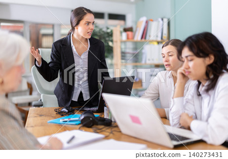 Standing girl scold to round table gathering female staff at office Standing girl scold to round table gathering female staff at office 140273431