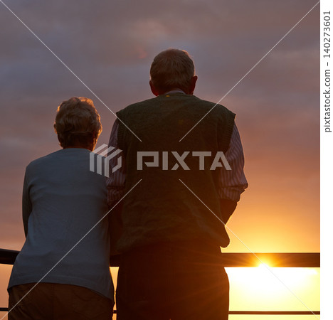 Senior couple, sunset and together on balcony in outdoors, bonding and love on vacation or holiday. Back, elderly people and dusk on terrace and together in nature, security and travel for marriage 140273601