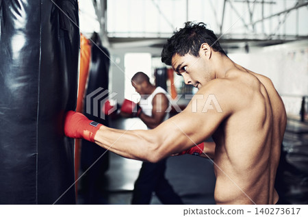 Fitness, punching bag and man with boxing gloves at a gym for training, resilience or performance. Sports, body and male boxer profile with punch practice for strength, energy for fighting exercise 140273617