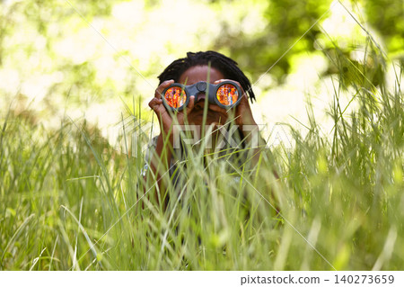 Nature, binoculars and child in grass for exploring in park on vacation, adventure or holiday. Travel, forest and young boy kid with equipment in lawn in outdoor field or woods on weekend trip. Nature, binoculars and child in grass for exploring in park on vacation, adventure or holiday. Travel, forest and young boy kid with equipment in lawn in outdoor field or woods on weekend trip. 140273659