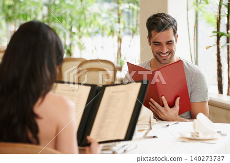 Happy couple, date and reading menu at restaurant for fine dining, romance or ordering food together. Young man and woman looking at brochure with smile for meal, dinner or decision in eating choice Happy couple, date and reading menu at restaurant for fine dining, romance or ordering food together. Young man and woman looking at brochure with smile for meal, dinner or decision in eating choice 140273787