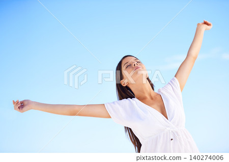Blue sky, sunshine and woman on holiday with freedom, happy adventure and low angle in Greece. Summer, smile and calm girl stretching arms for energy, wellness and outdoor travel vacation in nature 140274006