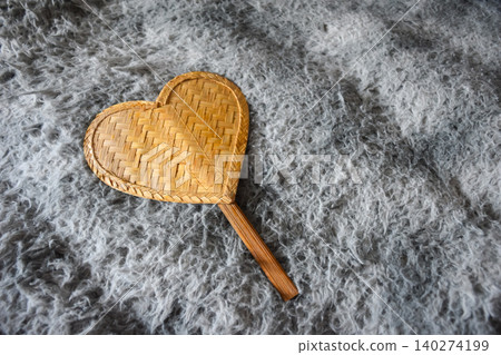 Handcrafted heart shaped bamboo hand fan resting soft gray textured fabric background natural weave detail copy space for love decor lifestyle handmade concepts Handcrafted heart shaped bamboo hand fan resting soft gray textured fabric background natural weave detail copy space for love decor lifestyle handmade concepts 140274199