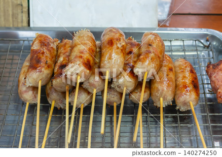 Freshly grilled sausage skewers stacked metal cooling rack golden browned surface juicy texture street food appeal ready to serve Freshly grilled sausage skewers stacked metal cooling rack golden browned surface juicy texture street food appeal ready to serve 140274250