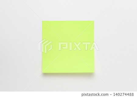 A photograph of a green sticky note taken from directly above against a white background. A photograph of a green sticky note taken from directly above against a white background. 140274488