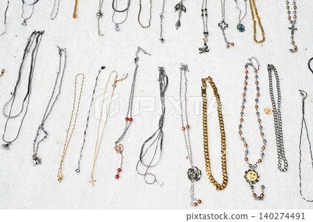 Assortment of various metal necklaces and chain jewelry displayed on white background for sale at street market in china 140274491