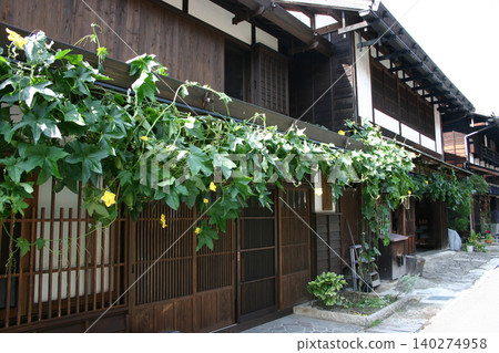 妻籠宿古老的街景和綠色的絲瓜絡在中山道(長野縣)沿線構成了一幅迷人的夏日景象。 妻籠宿古老的街景和綠色的絲瓜絡在中山道(長野縣)沿線構成了一幅迷人的夏日景象。 140274958