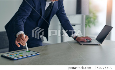 一名男子正在使用筆記型電腦和平板電腦工作。 一名男子正在使用筆記型電腦和平板電腦工作。 140275509