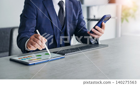 A man working using a smartphone and a tablet PC. A man working using a smartphone and a tablet PC. 140275563