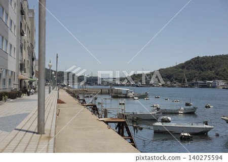 廣島縣尾道市，晴空萬裡之下，一艘小船漂浮在尾道海峽，港口小鎮的景色盡收眼底。 140275594