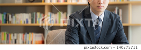 一幅英俊的年輕高管、首席執行官或商人坐在書架前,面帶微笑的肖像;一條沒有面孔的橫幅。 一幅英俊的年輕高管、首席執行官或商人坐在書架前,面帶微笑的肖像;一條沒有面孔的橫幅。 140275711