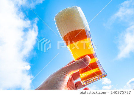 Beer held up against the blue sky 140275757