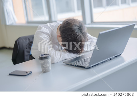 A tired businessman sleeping at his desk 140275808