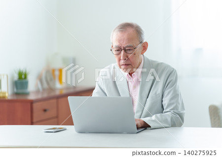 An elderly man using a computer with a troubled expression. An elderly man using a computer with a troubled expression. 140275925