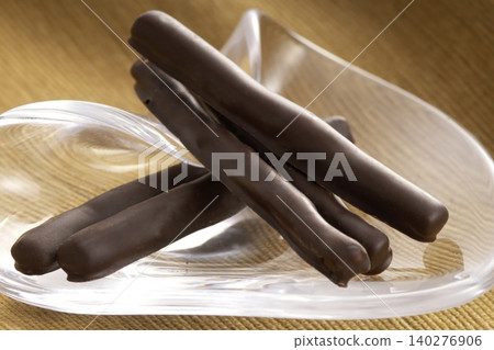 Chocolate-covered orange peel sticks served on a glass plate 140276906