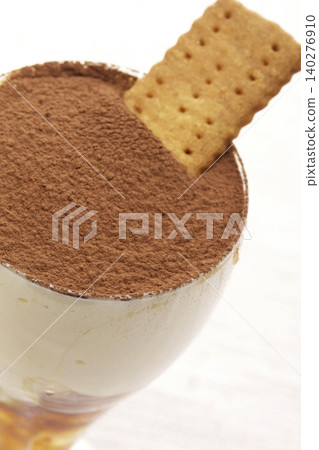 Glass dessert topped with cocoa powder and biscuits 140276910