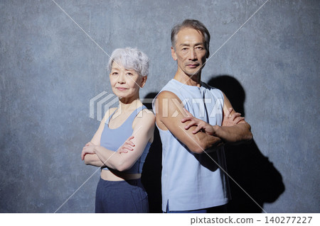 Portrait of a senior man and woman in sportswear against a black background, looking directly at the camera. Portrait of a senior man and woman in sportswear against a black background, looking directly at the camera. 140277227
