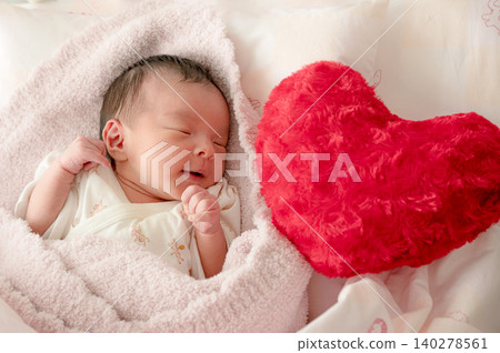 A newborn baby smiling next to a heart-shaped cushion A newborn baby smiling next to a heart-shaped cushion 140278561