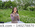 A woman eating a sandwich at a picnic. 140278870