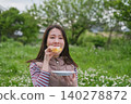A woman eating a sandwich at a picnic. 140278872