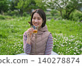 A woman drinking tea at a picnic. 140278874