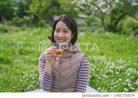 A woman drinking tea at a picnic. A woman drinking tea at a picnic. 140278874