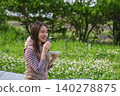 A woman eating rice balls at a picnic. 140278875