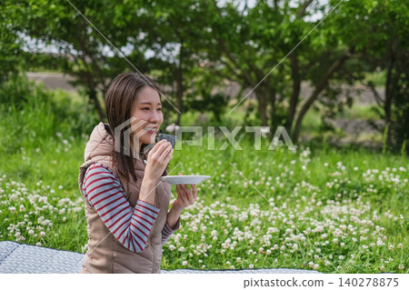 A woman eating rice balls at a picnic. A woman eating rice balls at a picnic. 140278875