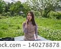 A woman eating rice balls at a picnic. 140278878