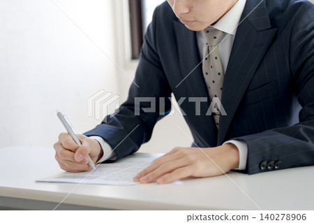A young man filling out a document. A young man filling out a document. 140278906