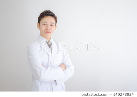 一位身穿白大褂、雙臂交叉的年輕男醫生。 140278924