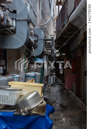 A narrow alleyway in a shopping street, with the road surface wet from the rain. A narrow alleyway in a shopping street, with the road surface wet from the rain. 140279590