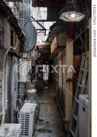 A narrow alleyway in a shopping street, with the road surface wet from the rain. A narrow alleyway in a shopping street, with the road surface wet from the rain. 140279591