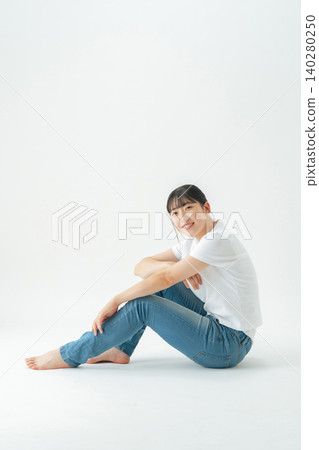 Full-body photo of a teenage girl wearing casual clothing sitting on the floor Full-body photo of a teenage girl wearing casual clothing sitting on the floor 140280250