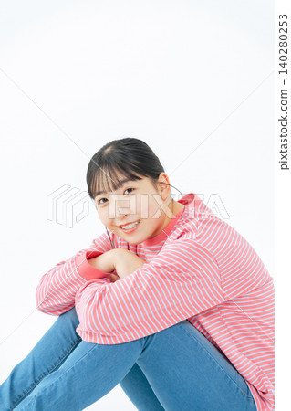 一名身穿休閒服、坐在地板上的少女的全身照片 一名身穿休閒服、坐在地板上的少女的全身照片 140280253