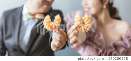 新郎新娘拿著甜甜圈拍婚紗照 新郎新娘拿著甜甜圈拍婚紗照 140280358