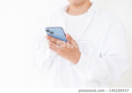 A middle-aged man in a white shirt holding a smartphone, against a white background. A middle-aged man in a white shirt holding a smartphone, against a white background. 140280437