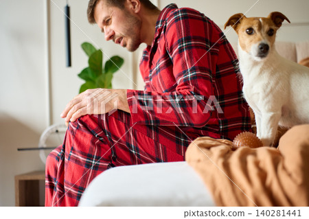 Man Suffering from Knee Pain on Bed with Jack Russell Terrier 140281441