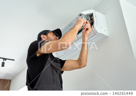 Man repairing air conditioner indoors Man repairing air conditioner indoors 140281449