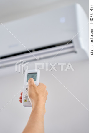 Hand using air conditioner remote Hand using air conditioner remote 140281455