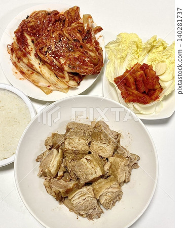 Tender slices of bossam, Korean boiled pork belly, served with fresh lettuce, garlic, and ssamjang. This flavorful and savory dish is perfect for wrapping and sharing in a traditional Korean meal. 140281737