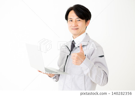 A middle-aged businessman in gray work clothes, holding a laptop and giving a thumbs-up, with a white background. A middle-aged businessman in gray work clothes, holding a laptop and giving a thumbs-up, with a white background. 140282356