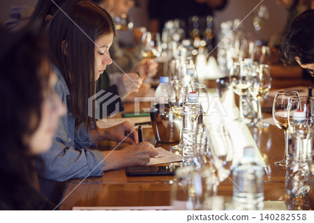 Female Sommelier Recording Tasting Notes During Wine Tasting Session Indoor Female Sommelier Recording Tasting Notes During Wine Tasting Session Indoor 140282558