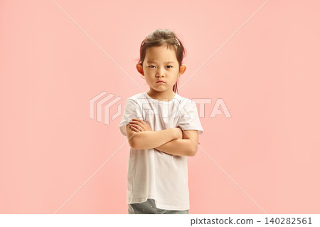 Offended Little Asian Girl Defiantly Crossed Arms in Front of Her Expressing Dissatisfaction and Resentment Standing Over Pink Isolated. Children Capricious Disposition and Negativity Concept. 140282561