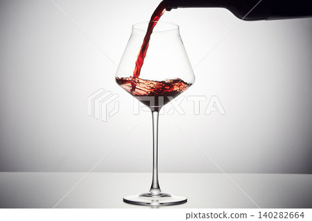 Red wine is poured from bottle into transparent glass. Red wine is poured from bottle into transparent glass. 140282664