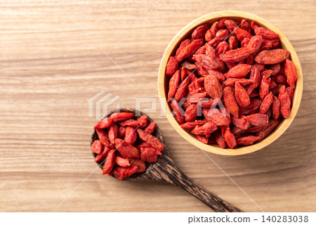 Organic dried goji berries in a bowl and spoon on wooden background. Healthy food. Table top view Organic dried goji berries in a bowl and spoon on wooden background. Healthy food. Table top view 140283038