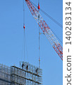 A construction worker assembling temporary scaffolding using a tower crane. 140283134