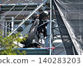 Scenes from the assembly of temporary scaffolding and installation of protective sheets during large-scale renovation of an apartment building. 140283203